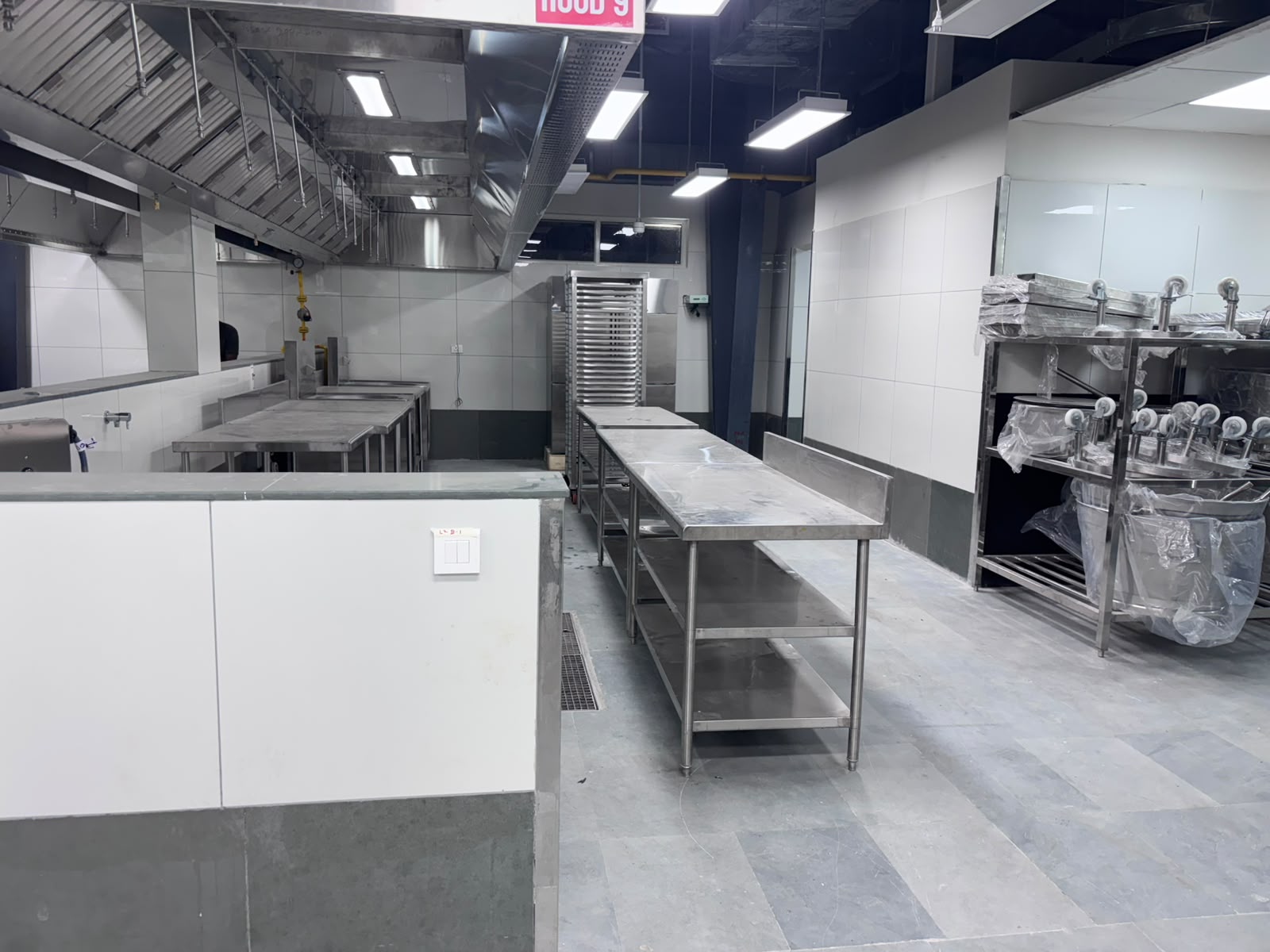 Commercial kitchen installation - stainless steel work tables under exhaust hood